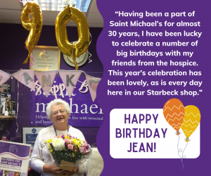 Alt text: Jean holding flowers standing behind the till with golden 90th birthday balloons above her head